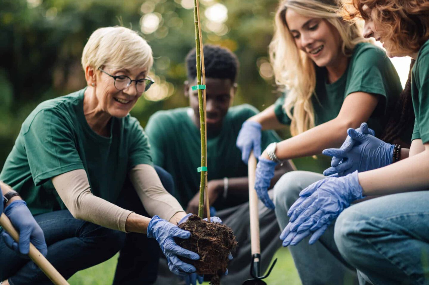 Happy volunteers planting a tree in the park